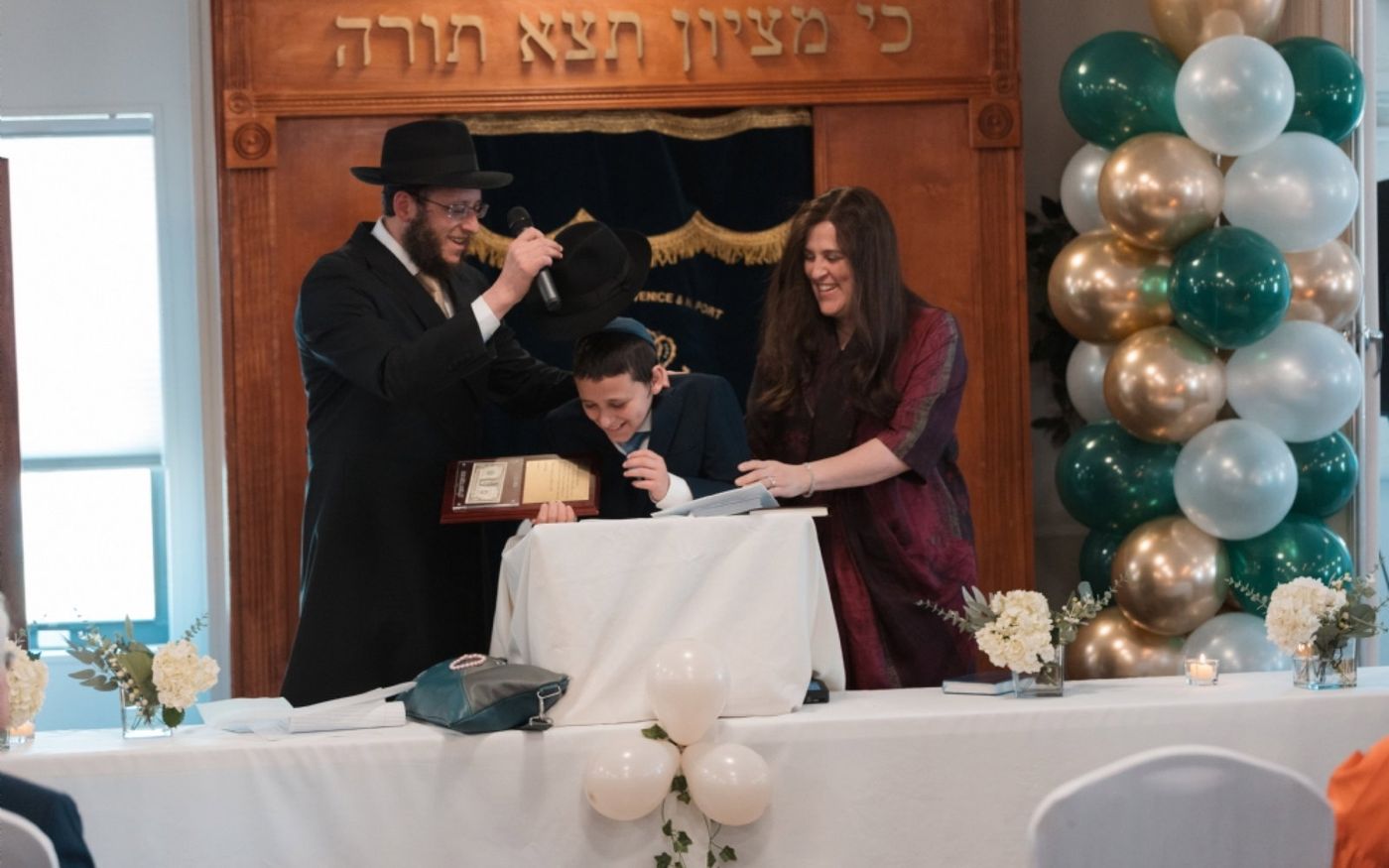 A student being celebrated at the front of the sanctuary at Chabad of Venice, balloons framing the ark