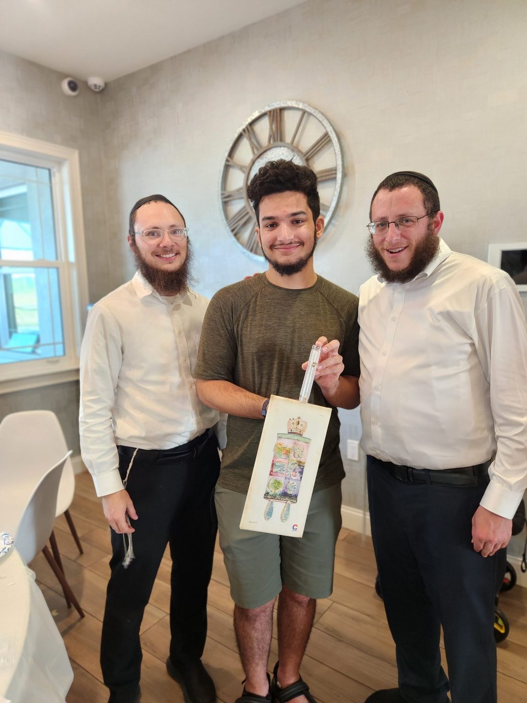 Devin with two rabbis, holding a gift bag