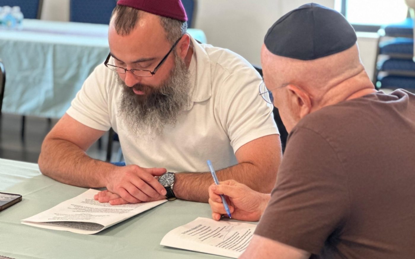 Two men studying a text together at a table at Chabad of Venice