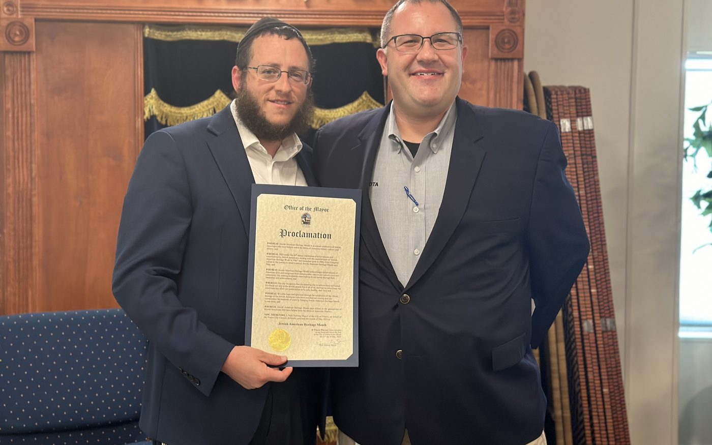 Rabbi Sholom Schmerling holding the City of Venice proclamation beside City Manager Ed Lavallee in front of the ark