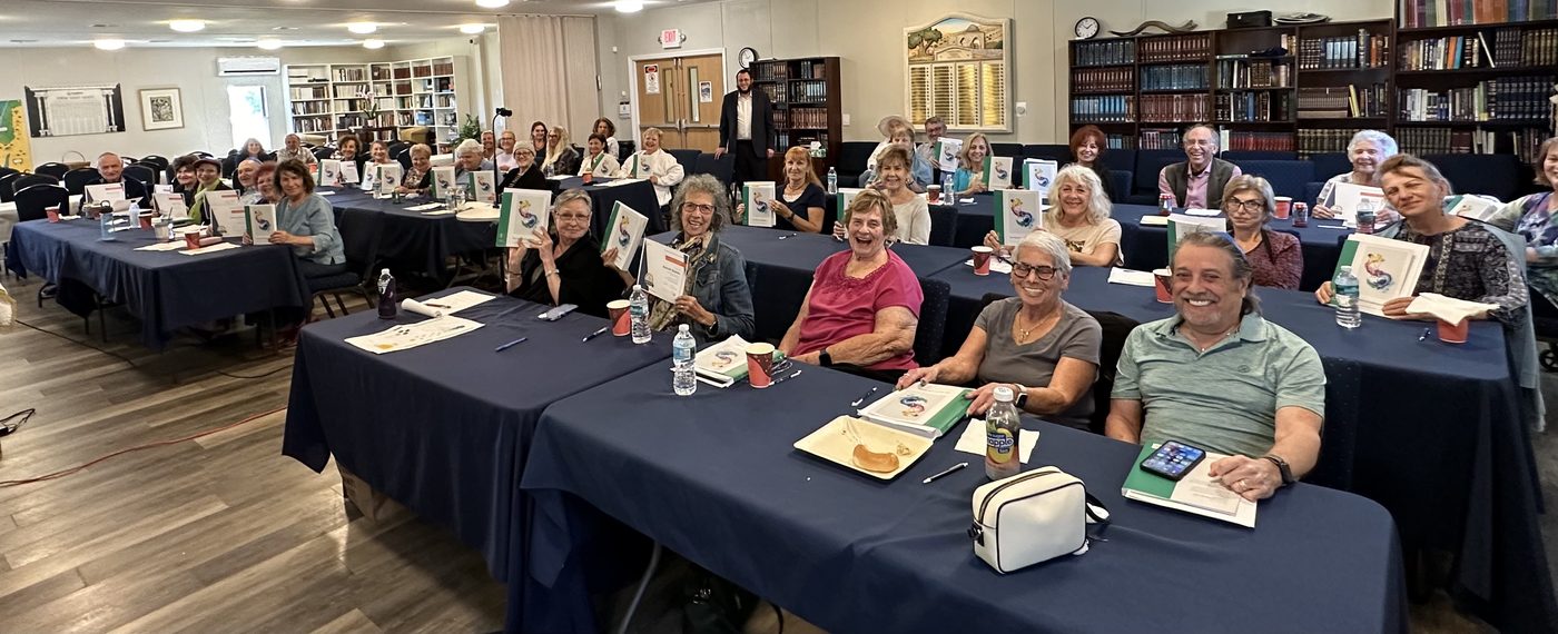 Adult students seated at long tables in a JLI class at Chabad of Venice, course books open