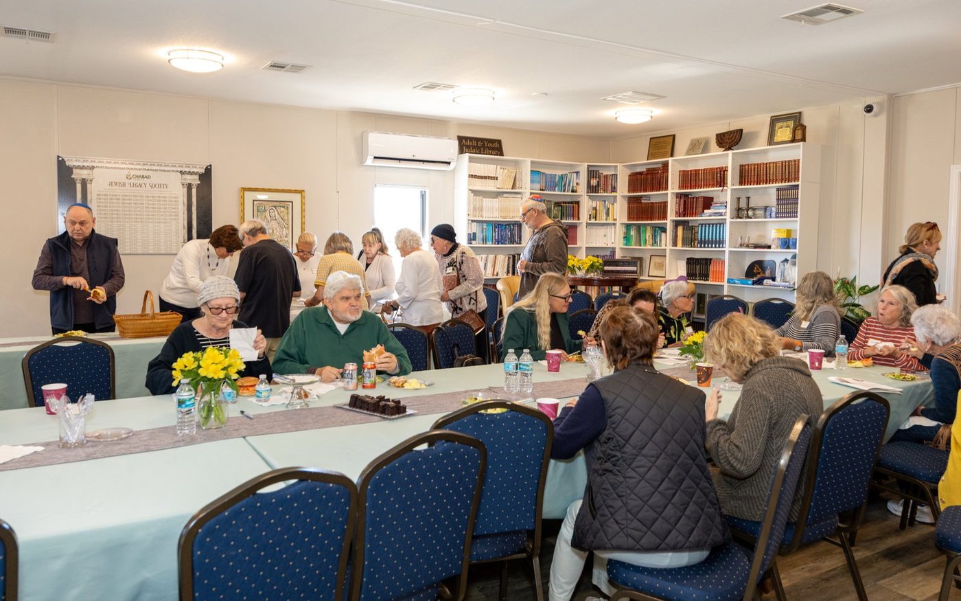 Women seated around the tables at a Chabad of Venice class, books open in front of them