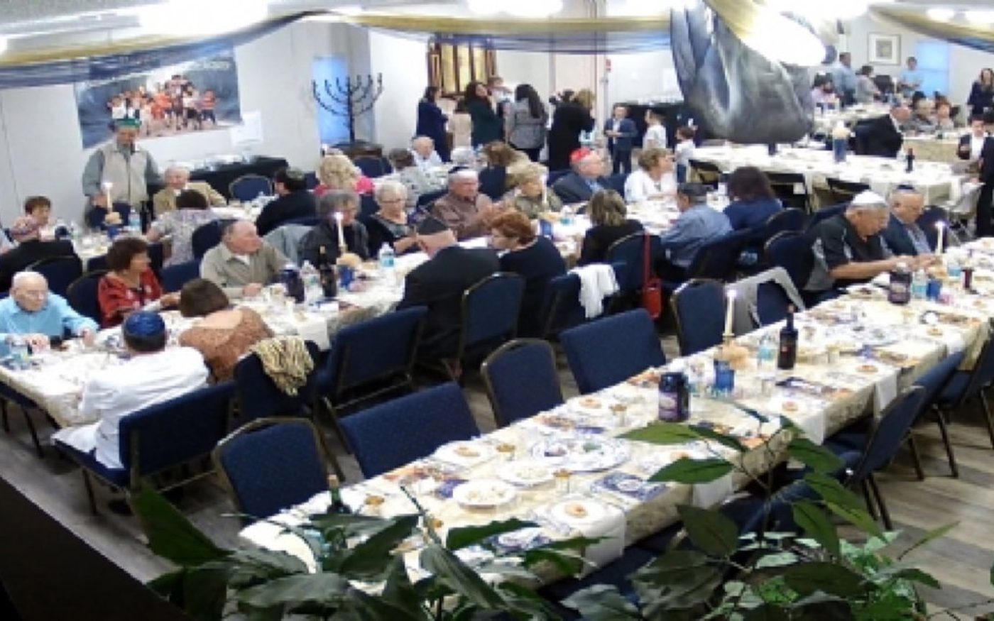 Long tables set for the community Seder at Chabad of Venice, guests seated the length of the hall
