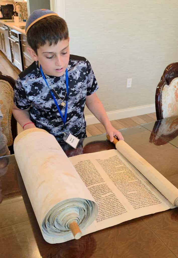Michael Tompakov chants from the restored Holocaust Torah, unrolled before him