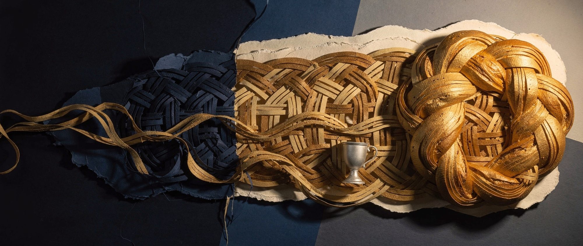 Papercut braided challah whose strands open into a woven ribbon, a silver kiddush cup among them