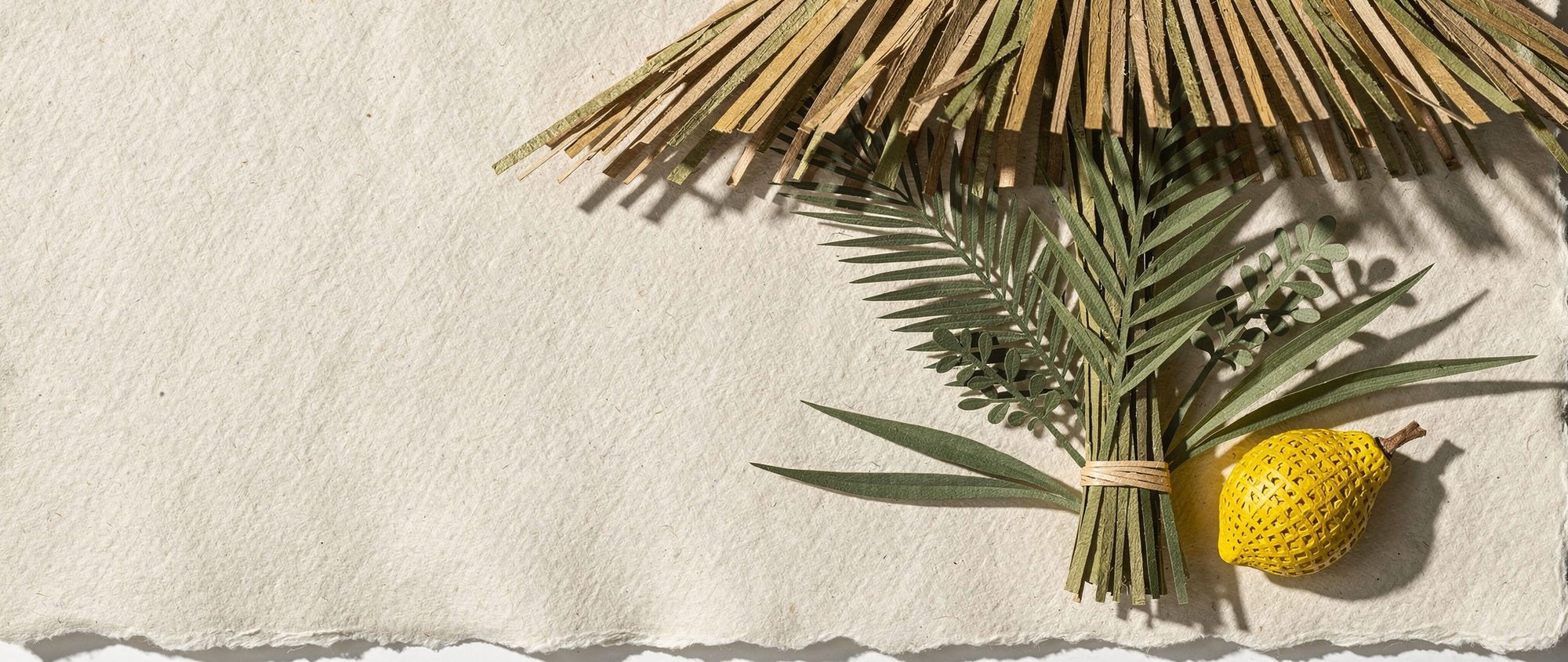 Papercut lulav and etrog under palm thatch